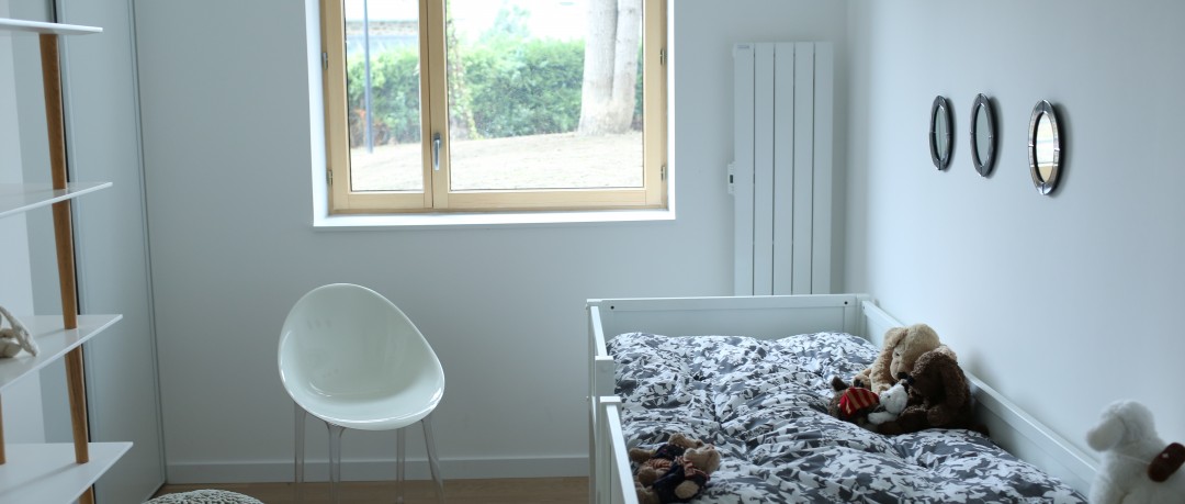 Chambre blanche avec lit pour enfant et radiateur mural