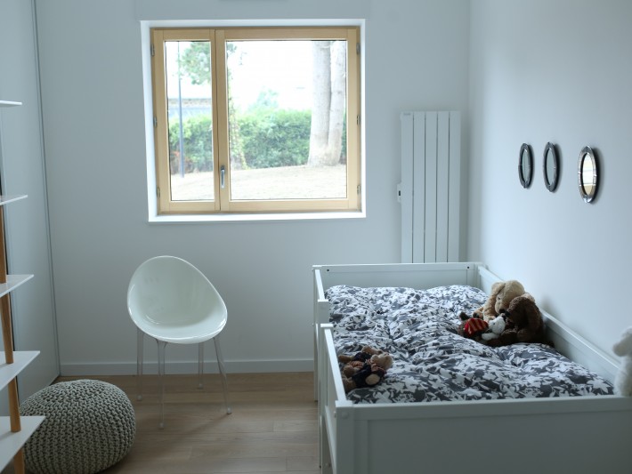 Chambre blanche avec lit pour enfant et radiateur mural