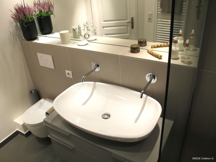 Grande vasque blanche avec deux robinets posée sur un meuble de rangements