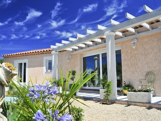 Maison individuelle avec pergola et terrasse entourant la maison